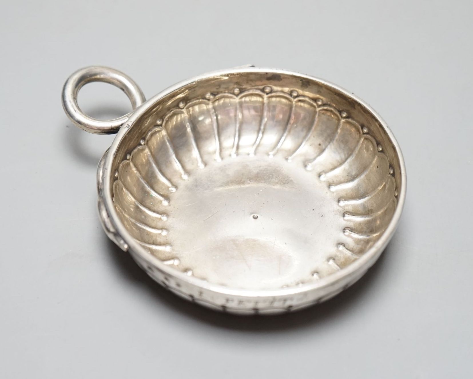 A late 18th/early 19th century French white metal taste vin, with engraved inscription and ring handle, 11.6cm over handle, 122 grams.